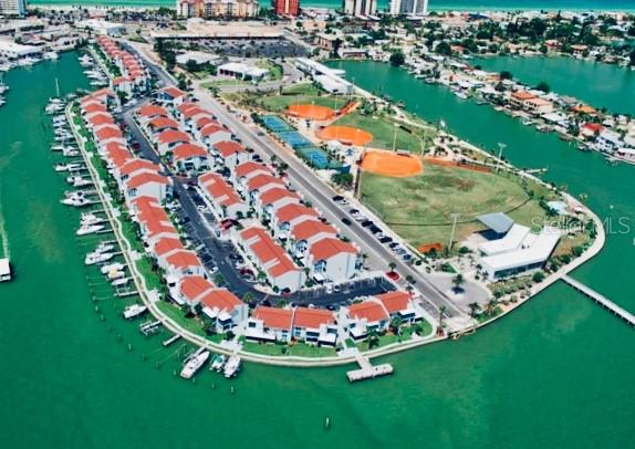 An aerial view shows a waterfront residential complex with a park, tennis courts, and boat slips — 171 MEDALLION BOULEVARD UNIT B, MADEIRA BEACH, FL