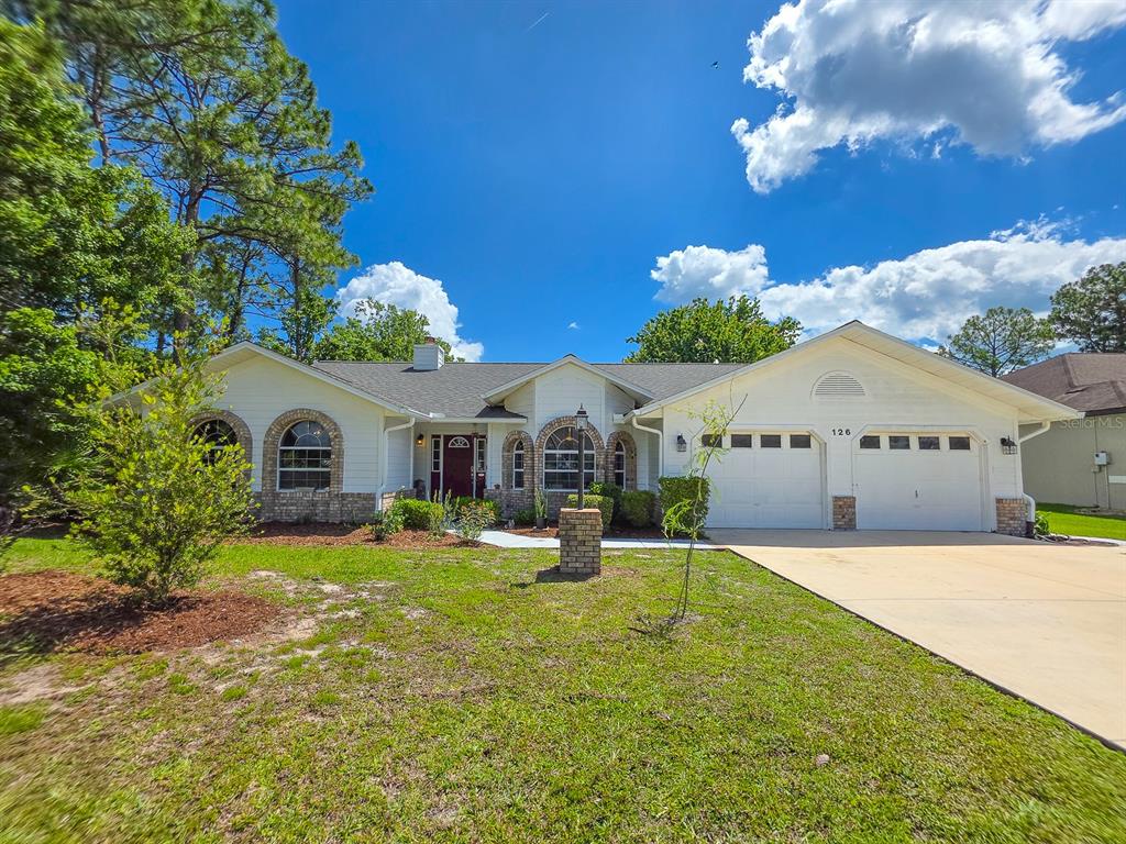 A single-story house with a white exterior, brick accents, and a two-car garage — 126 BIRCHWOOD DRIVE, PALM COAST, FL