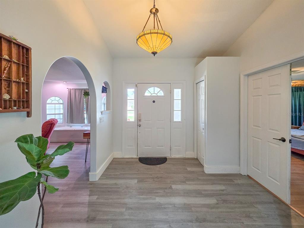 An entryway features light wood-look flooring, a white front door, and an arched doorway — 126 BIRCHWOOD DRIVE, PALM COAST, FL