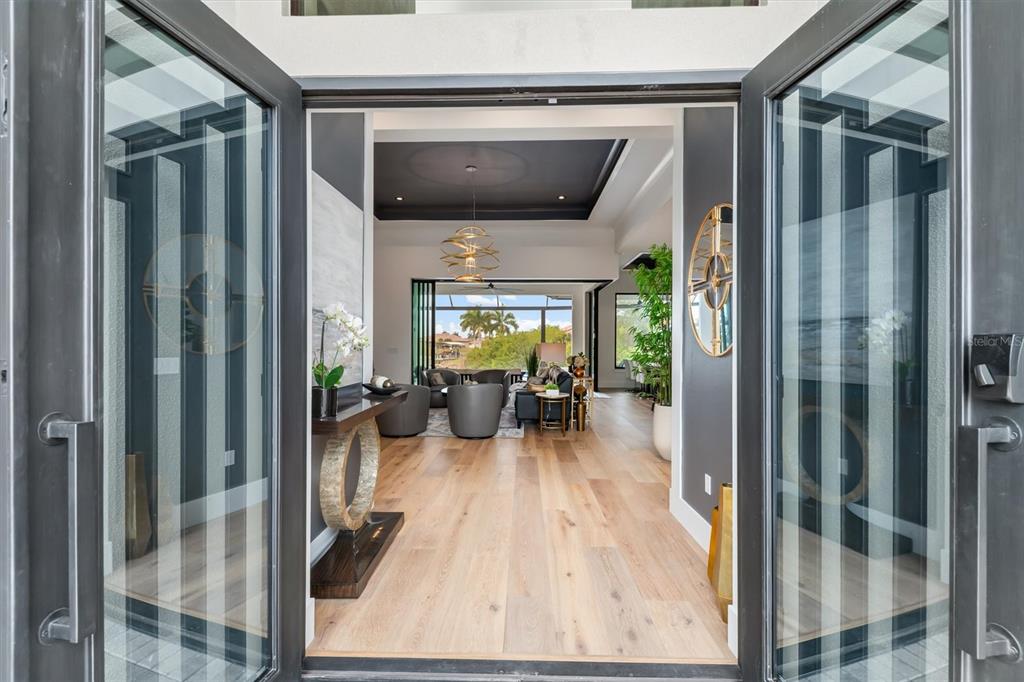 A view through an open double door into a modern living room with hardwood floors — 9474 MELODY CIRCLE, PORT CHARLOTTE, FL