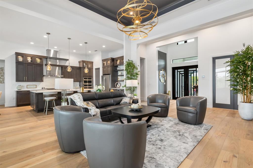 An open-concept living room and kitchen featuring dark cabinetry, hardwood floors, and a gold chandelier — 9474 MELODY CIRCLE, PORT CHARLOTTE, FL