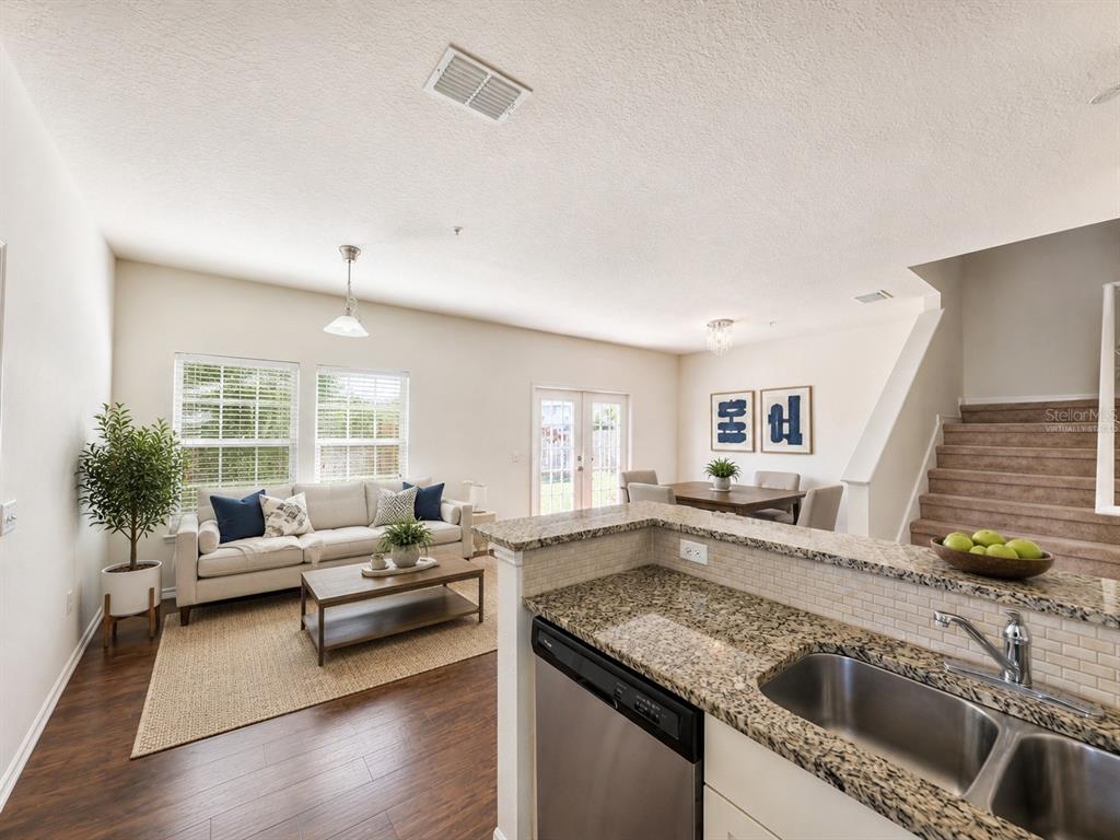 A kitchen with granite countertops overlooks a living room and dining area with stairs — 3208 OYSTER LANE, KISSIMMEE, FL