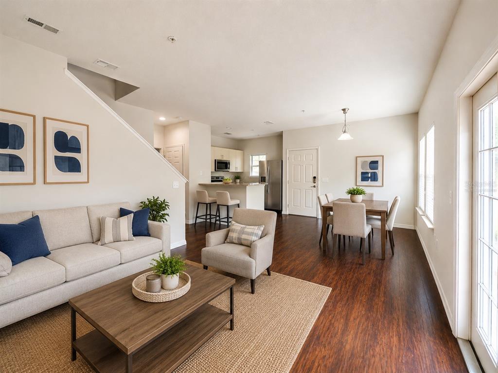 An open-concept living and dining area features wood-look flooring, neutral walls, and modern furniture — 3208 OYSTER LANE, KISSIMMEE, FL