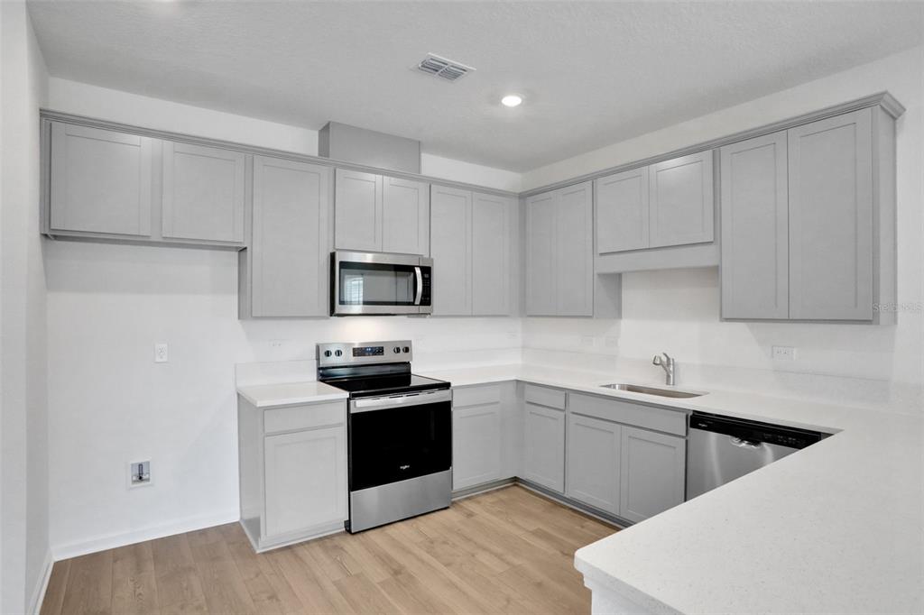 A kitchen features light gray cabinets, stainless steel appliances, and white countertops — 5792 LAGOON CRUISE WAY, JACKSONVILLE, FL