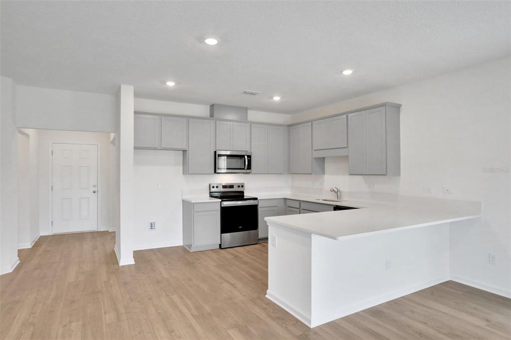 A kitchen with light gray cabinets, stainless steel appliances, and a white peninsula countertop — 5792 LAGOON CRUISE WAY, JACKSONVILLE, FL