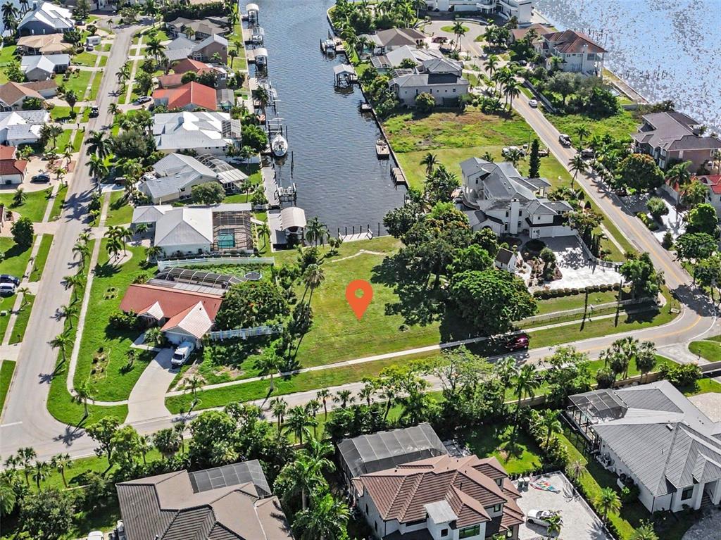 An aerial view shows a vacant waterfront lot marked with a pin in a residential neighborhood — 180 COUSLEY DRIVE SE, PORT CHARLOTTE, FL