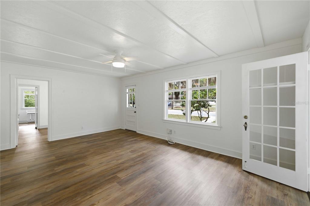 An empty room with white walls, wood-look flooring, a ceiling fan, and a glass-paned door — 923 NE 2ND STREET, OCALA, FL