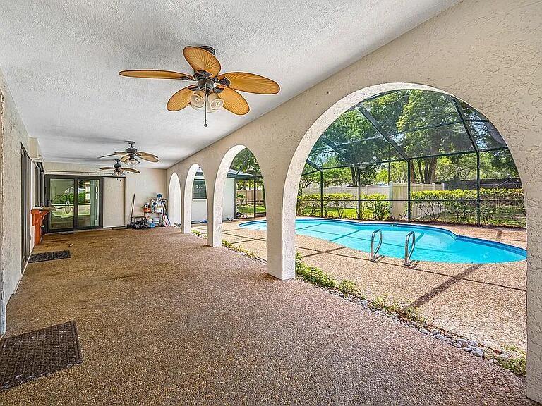 A covered patio with arched openings overlooks a screened-in swimming pool — 10 LINDEN LANE, PALM HARBOR, FL