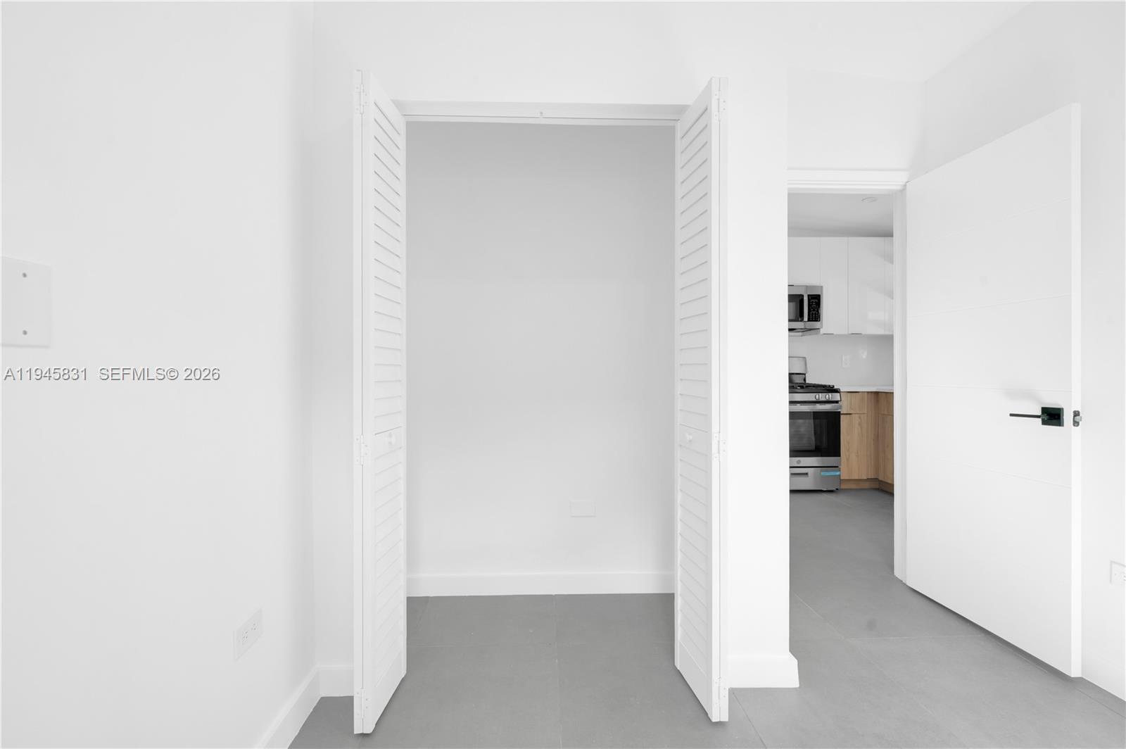 An interior view shows a closet with louvered doors next to a doorway leading to a kitchen — 3040 NW 93rd # D, Miami FL 33147, MIAMI, FL