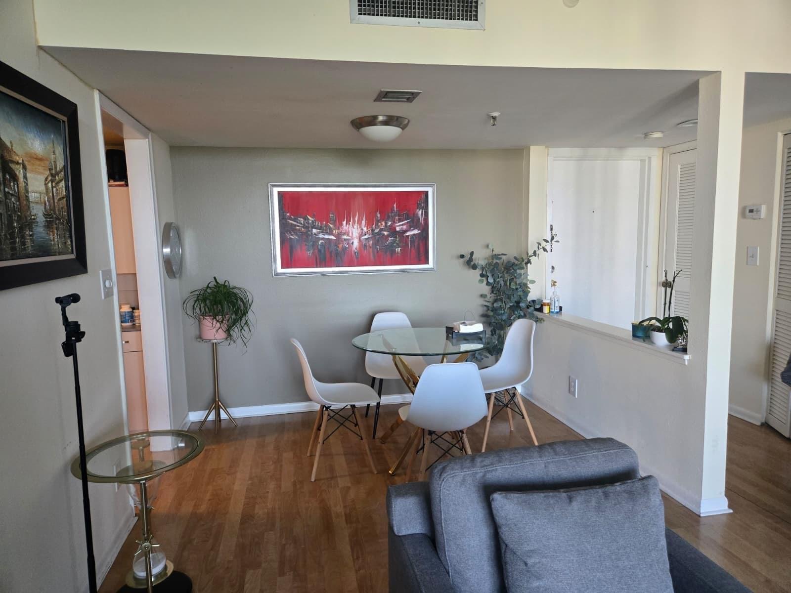 A dining area with a glass table, four white chairs, and a large red wall painting — 6797 Willow Wood Drive # 6073, Boca Raton FL 33434, BOCA RATON, FL
