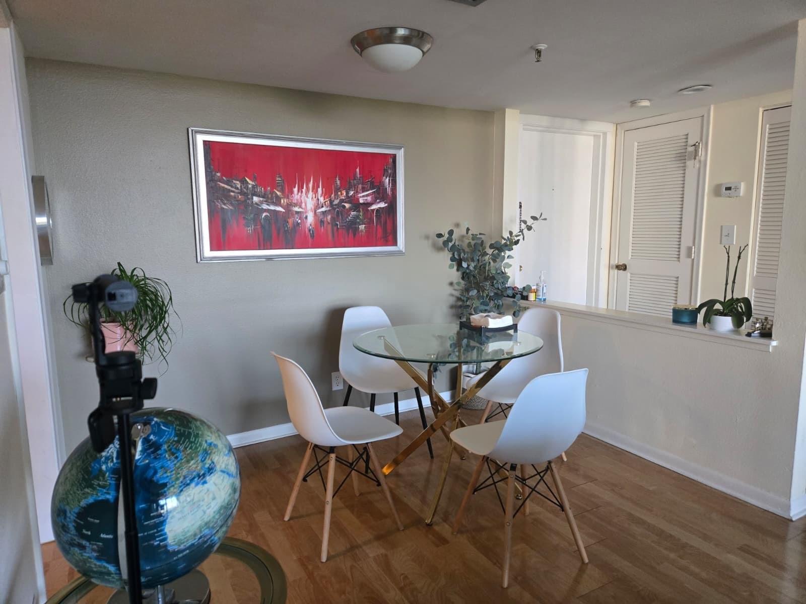 A dining area features a glass table with four white chairs and a red painting — 6797 Willow Wood Drive # 6073, Boca Raton FL 33434, BOCA RATON, FL
