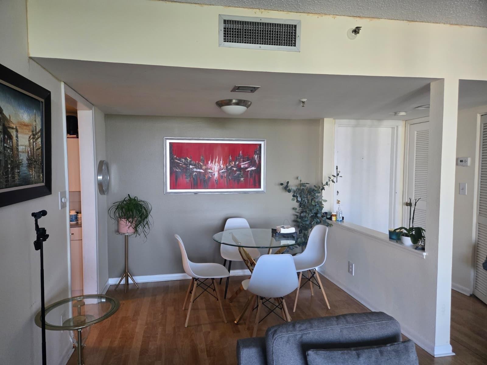 A dining area features a glass-top table, four white chairs, and a red abstract painting — 6797 Willow Wood Drive # 6073, Boca Raton FL 33434, BOCA RATON, FL