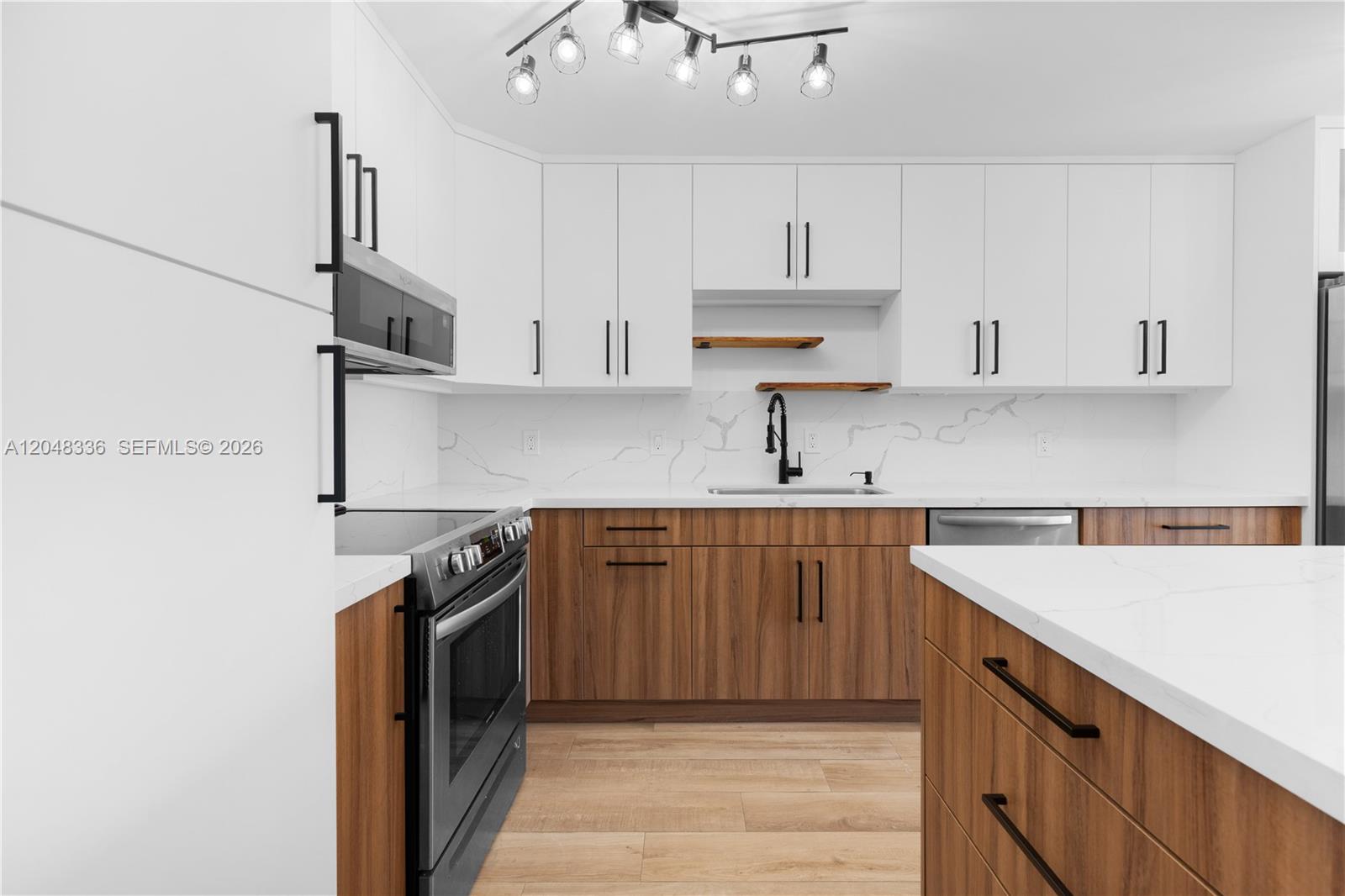 A modern kitchen features white upper cabinets, wood-tone lower cabinets, and white quartz countertops — 8752 SW 12th St # 201, Miami FL 33174, MIAMI, FL