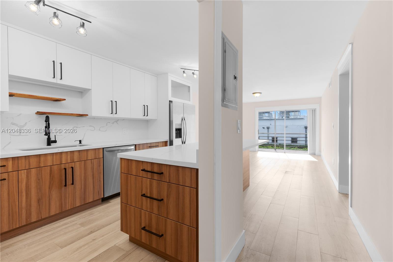 A modern kitchen features wood-grain lower cabinets, white upper cabinets, and a white countertop — 8752 SW 12th St # 201, Miami FL 33174, MIAMI, FL