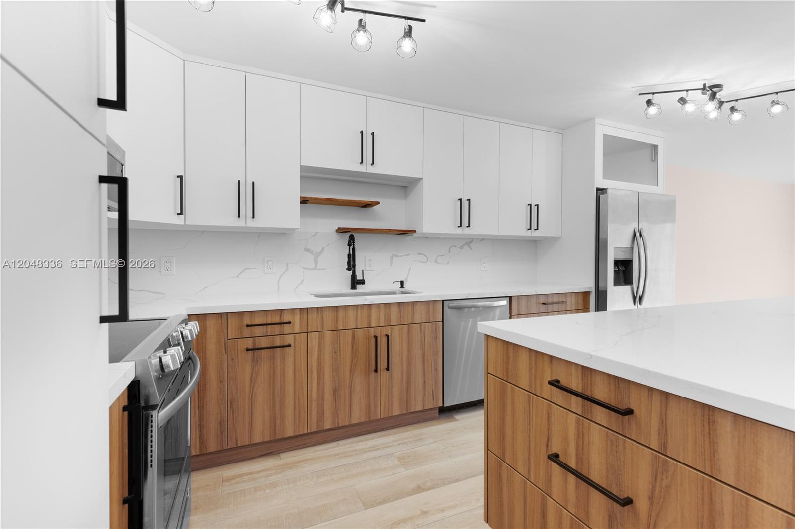 A modern kitchen features white upper cabinets, wood-grain lower cabinets, and a white quartz island — 8752 SW 12th St # 201, Miami FL 33174, MIAMI, FL