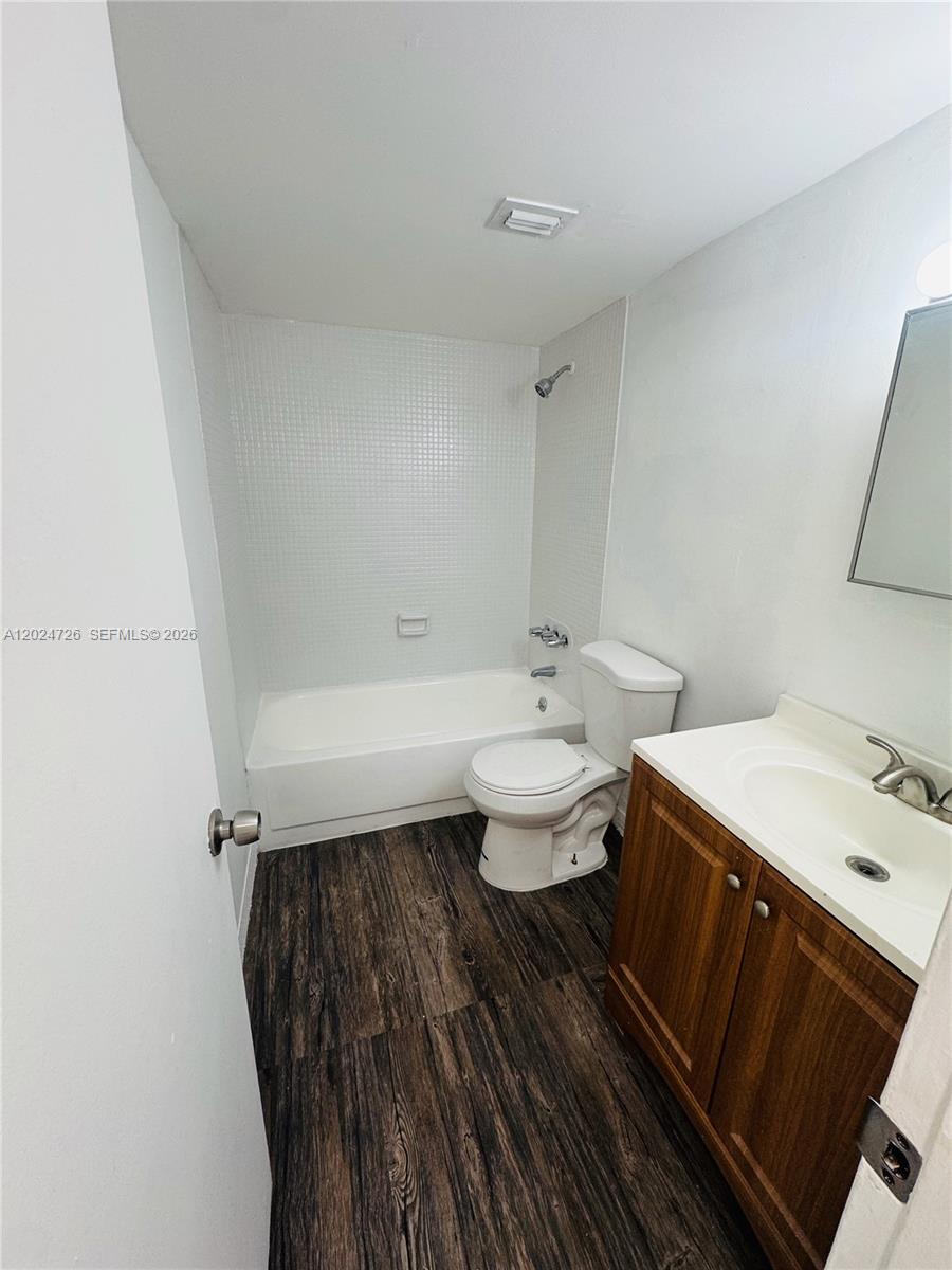 A bathroom features a white tub, a toilet, and a wood-toned vanity with a sink — 486 NW 165th St Rd # 201, Miami FL 33169, MIAMI, FL