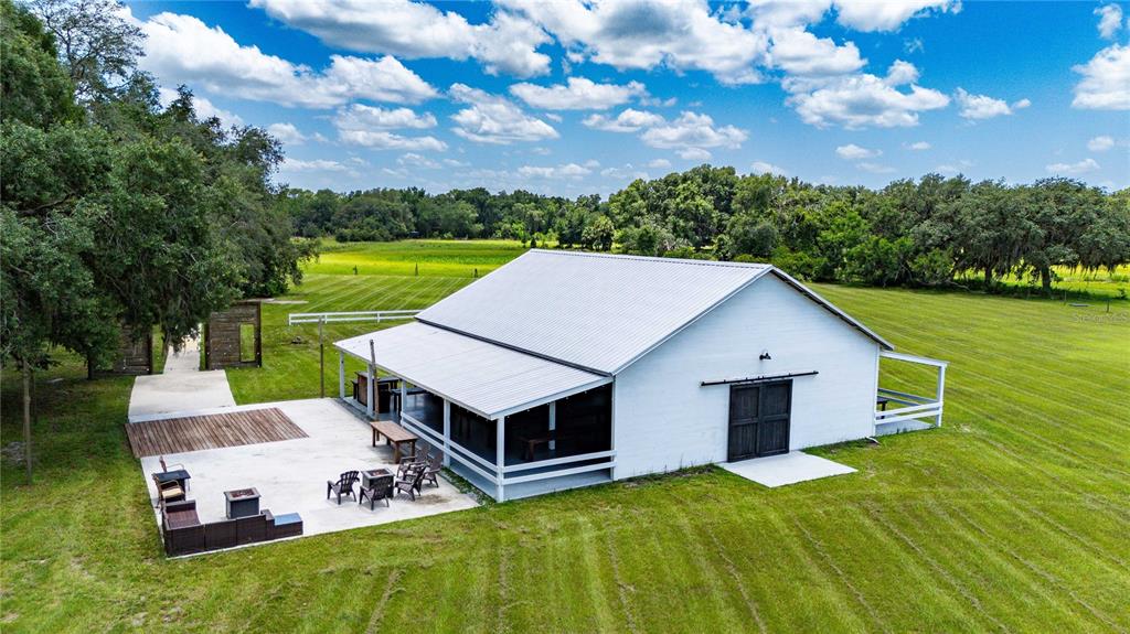 An aerial view of a white barn-style building with a patio and large grassy field — 4773 SW 47TH BOULEVARD, BUSHNELL, FL