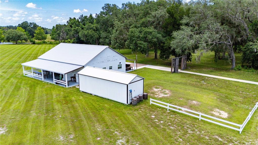 An aerial view shows a white barn with a porch and a detached shed on grass — 4773 SW 47TH BOULEVARD, BUSHNELL, FL