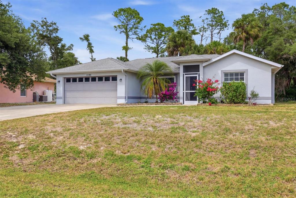A single-story house with a gray garage, light-colored siding, and a landscaped front yard — 3186 MARITA AVENUE, NORTH PORT, FL