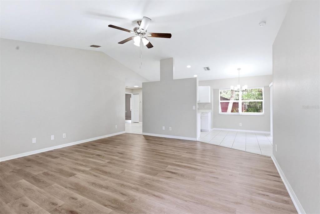 A living room with light wood-look flooring, a ceiling fan, and an adjacent tiled dining area — 3186 MARITA AVENUE, NORTH PORT, FL