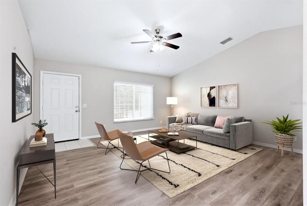 A living room features light wood-look flooring, a gray sofa, two tan chairs, and a rug — 3186 MARITA AVENUE, NORTH PORT, FL