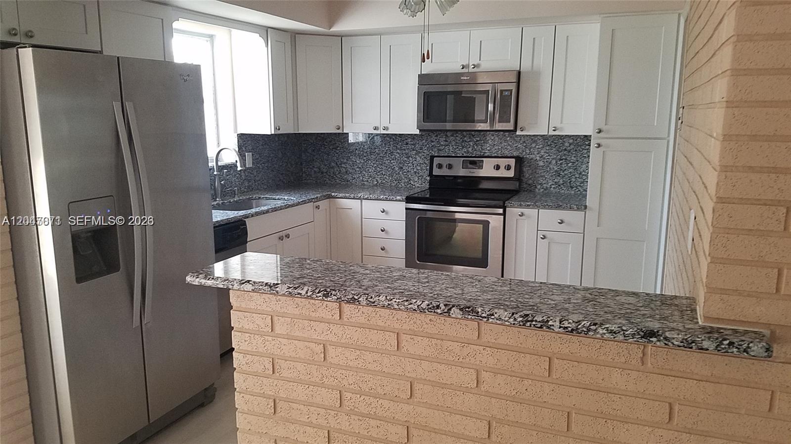 A kitchen features white cabinets, granite countertops, stainless steel appliances, and a brick breakfast bar — 3346 Coolidge St, Hollywood FL 33021, HOLLYWOOD, FL