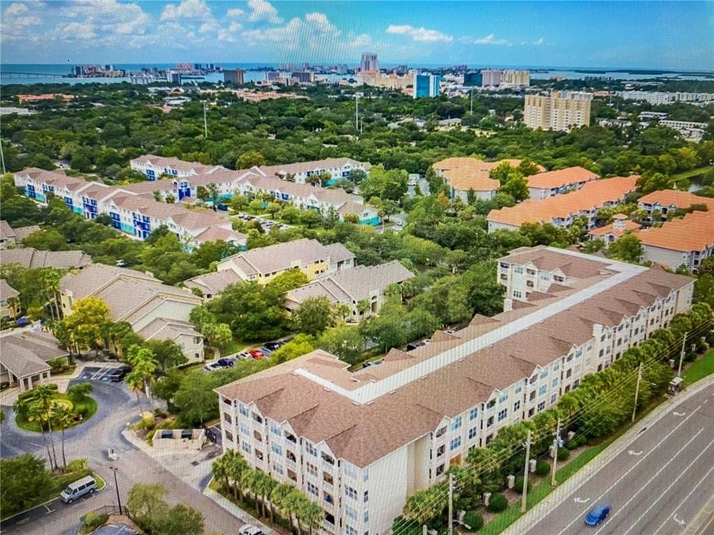 An aerial view shows a large apartment complex with multiple buildings, parking lots, and landscaping — 1216 S MISSOURI AVENUE UNIT 406, CLEARWATER, FL