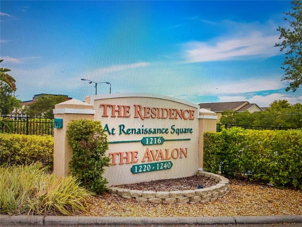A beige stone monument sign displays the names of a residential community and building numbers — 1216 S MISSOURI AVENUE UNIT 406, CLEARWATER, FL