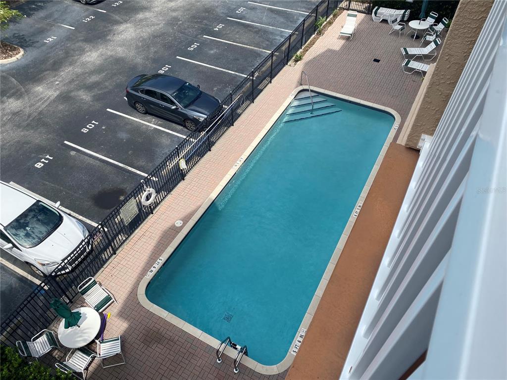 An elevated view shows a rectangular swimming pool next to a parking lot and patio — 1216 S MISSOURI AVENUE UNIT 406, CLEARWATER, FL