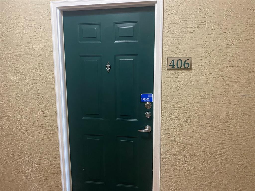 A dark green apartment door with a security sticker and the number 406 attached — 1216 S MISSOURI AVENUE UNIT 406, CLEARWATER, FL