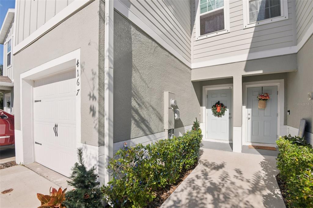 A two-story townhouse exterior features a garage, two light blue entry doors, and landscaping — 4167 HARBOUR PALM DRIVE, HOLIDAY, FL