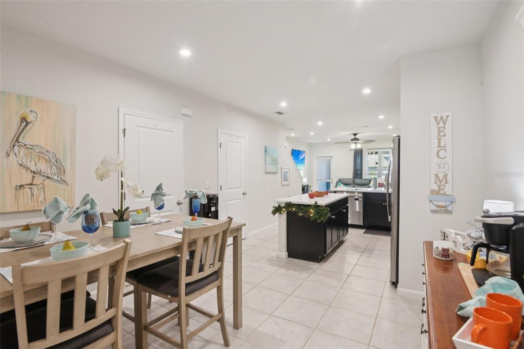 A dining area with a wooden table leads into an open kitchen with dark cabinets — 4167 HARBOUR PALM DRIVE, HOLIDAY, FL