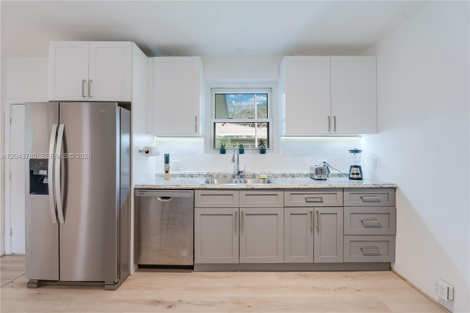 A kitchen features white upper cabinets, gray lower cabinets, stainless steel appliances, and granite countertops — 820 SW 26th Rd, Miami FL 33129, MIAMI, FL