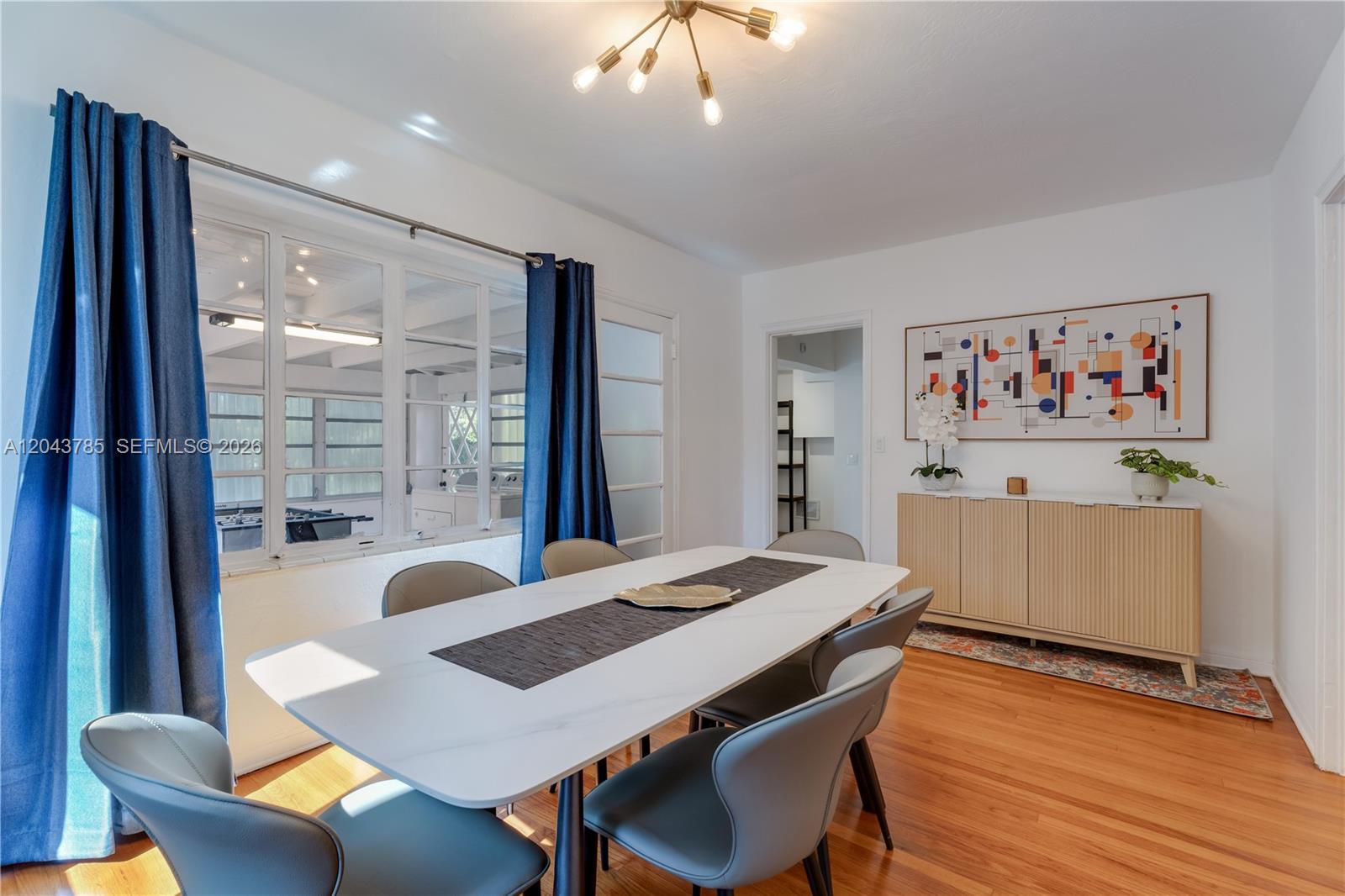 A dining room features a white table, grey chairs, a sideboard, and blue curtains — 820 SW 26th Rd, Miami FL 33129, MIAMI, FL