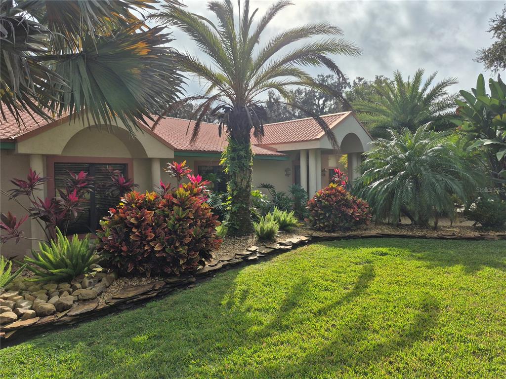 A single-story house with a red tile roof and lush tropical landscaping in the front — 4345 CORLEY ISLAND ROAD, LEESBURG, FL