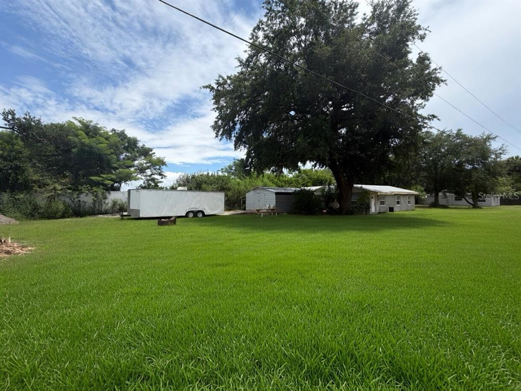 A large grassy yard features a white trailer and a small house under a tree — 3316 W 5TH STREET, SANFORD, FL