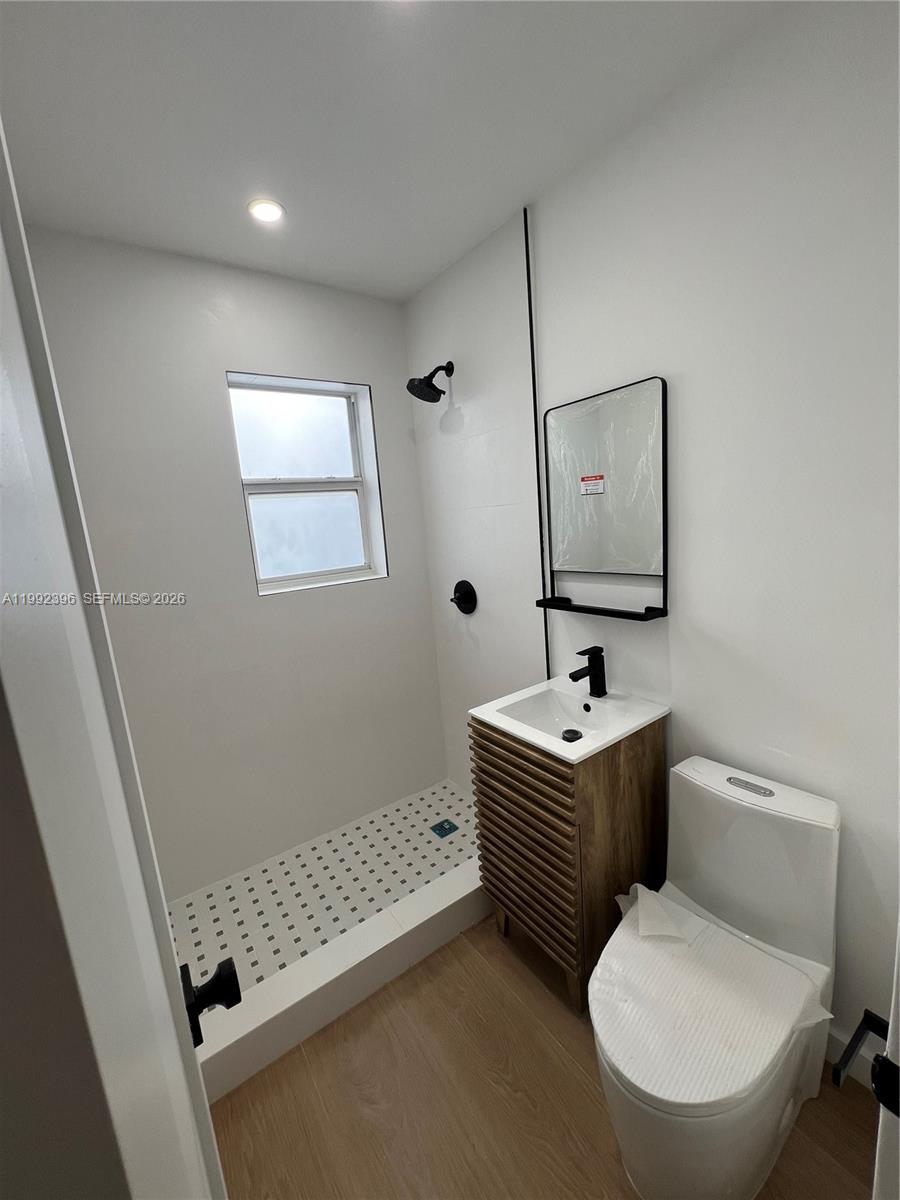 A small bathroom features a walk-in shower, a wooden vanity, and a white toilet — 7035 NE 4th Ct # 4, Miami FL 33138, MIAMI, FL