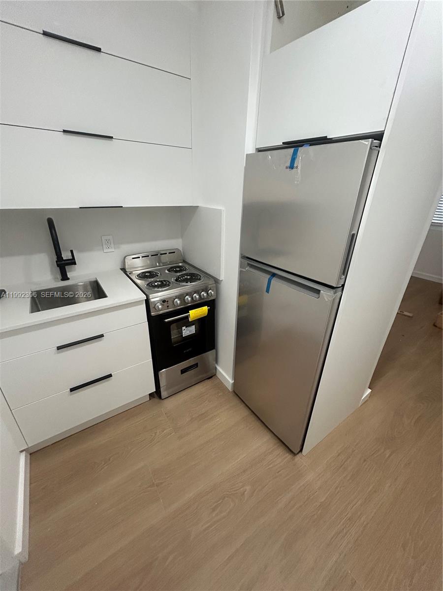 A small kitchen features white cabinets, a stainless steel stove, and a stainless steel refrigerator — 7035 NE 4th Ct # 4, Miami FL 33138, MIAMI, FL