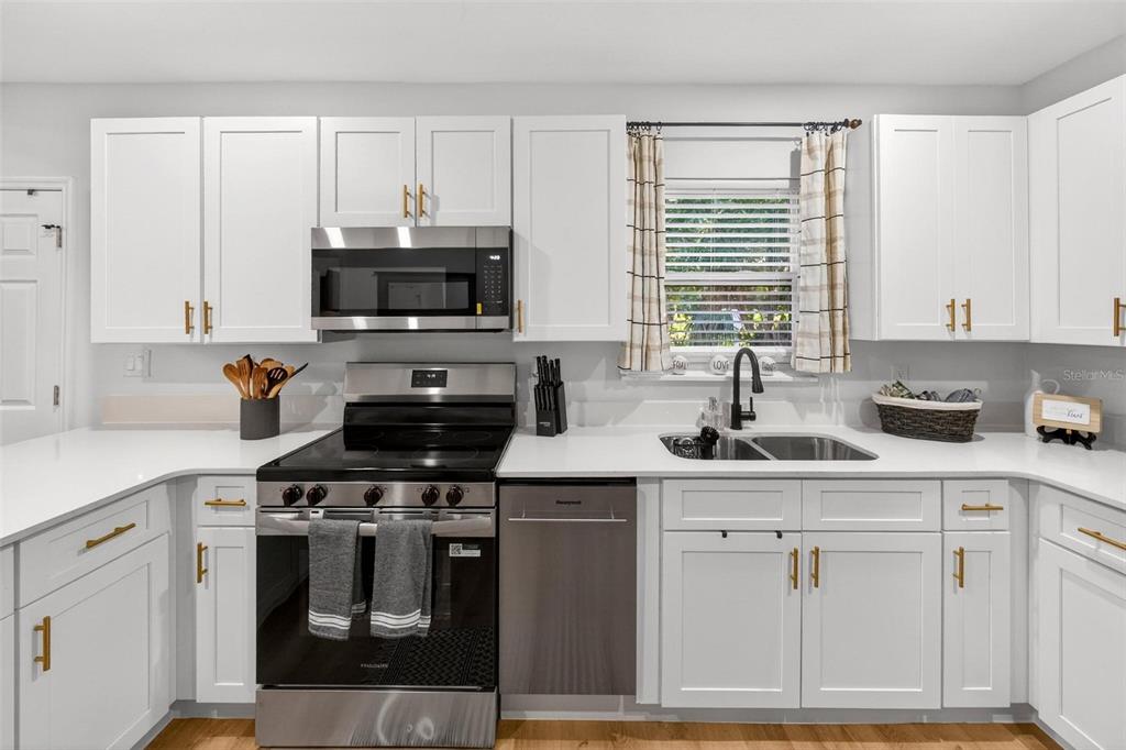 A kitchen features white cabinets, stainless steel appliances, a white countertop, and a double sink — 1503 GRANITE STATE COURT, MOUNT DORA, FL