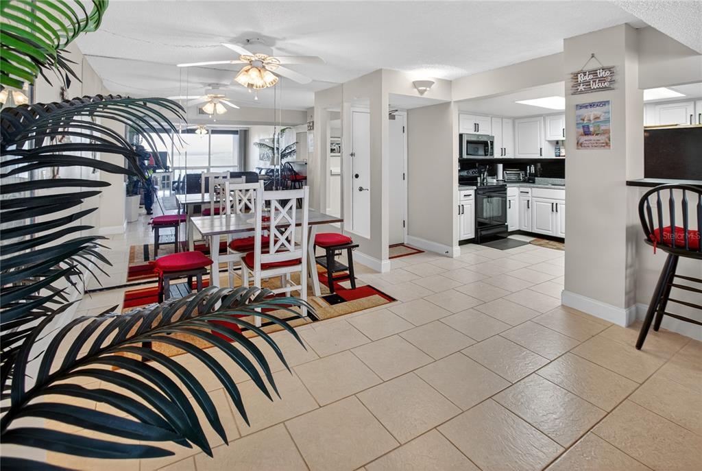 An open-concept dining area and kitchen feature white cabinets, tile flooring, and a ceiling fan — 1 KEY CAPRI UNIT 103E, TREASURE ISLAND, FL