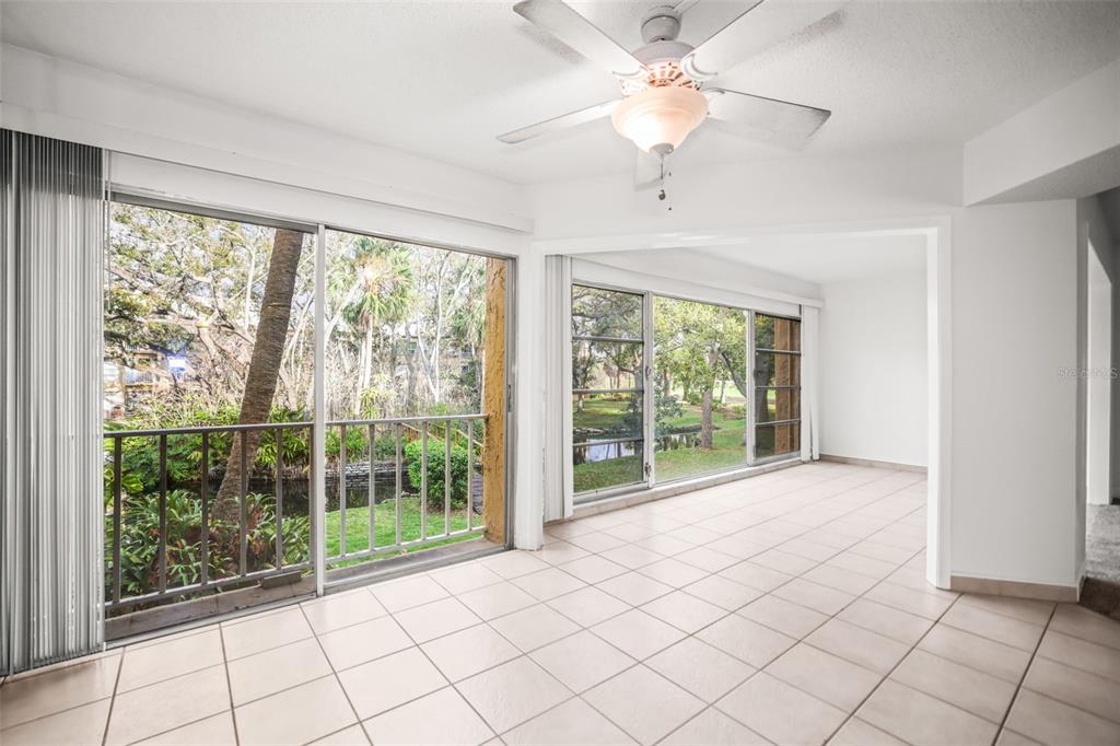 A sunroom with tile flooring, a ceiling fan, and large sliding glass doors overlooking greenery — 225 COUNTRY CLUB DRIVE UNIT D237, LARGO, FL