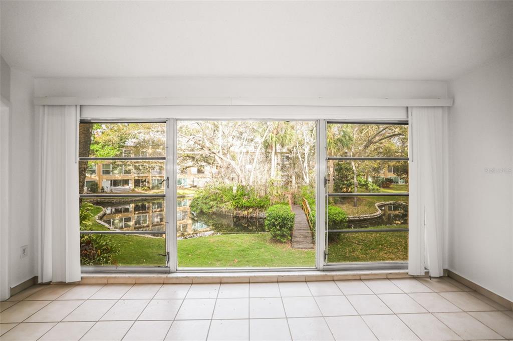 A room with white tile floors and a large window overlooking a pond and bridge — 225 COUNTRY CLUB DRIVE UNIT D237, LARGO, FL