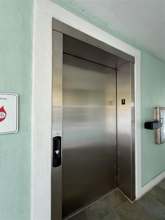 A stainless steel elevator door is set into a light green wall on the third floor — 5119 MELBOURNE STREET UNIT C304, PUNTA GORDA, FL