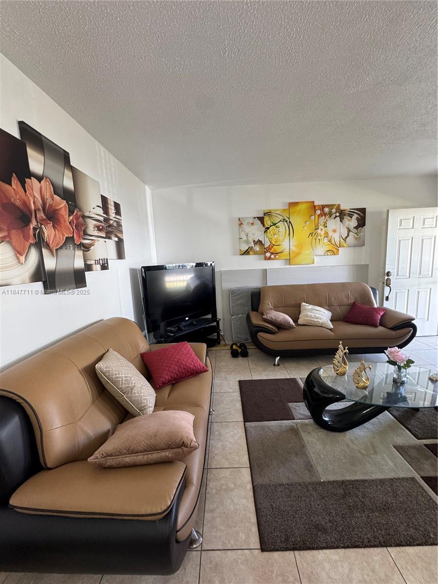 A living room features two tan and black sofas, a glass coffee table, and wall art — 71 NW 76th St # 5, Miami FL 33150, MIAMI, FL