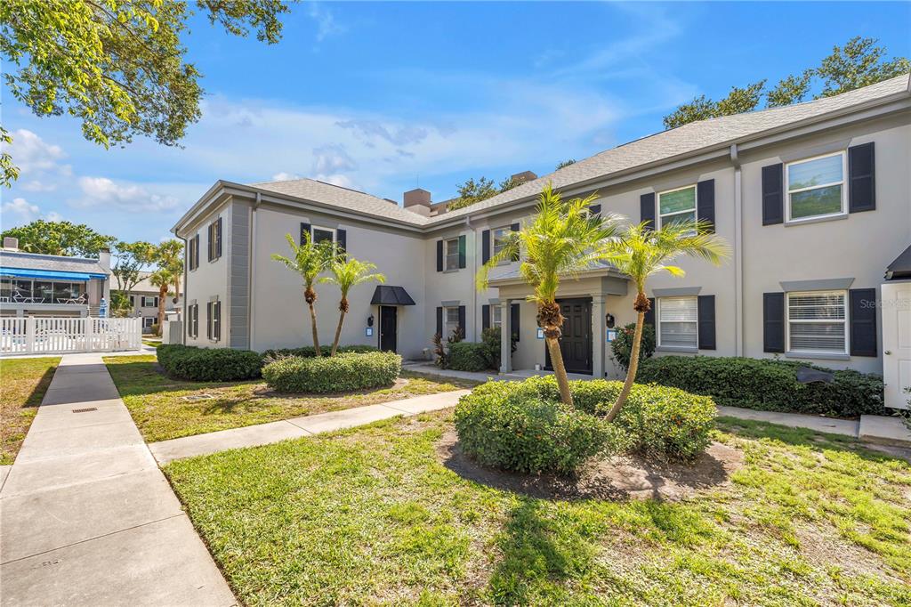 A two-story apartment building with a gray exterior, black shutters, and a landscaped front yard — 6960 SUNSET DRIVE S UNIT 1A, SOUTH PASADENA, FL