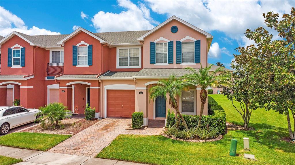 A two-story townhouse with a peach-colored exterior, a single-car garage, and a brick driveway — 864 PARK GROVE COURT, ORLANDO, FL