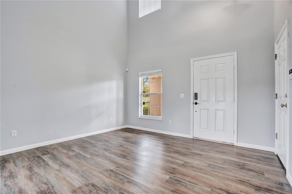 An empty room with high ceilings, light gray walls, and wood-look laminate flooring — 864 PARK GROVE COURT, ORLANDO, FL