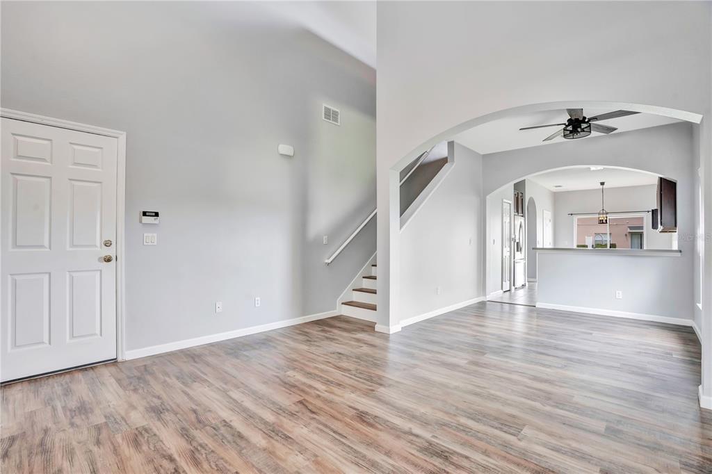 An open-concept living area features light gray walls, wood-look flooring, a staircase, and arched entryways — 864 PARK GROVE COURT, ORLANDO, FL