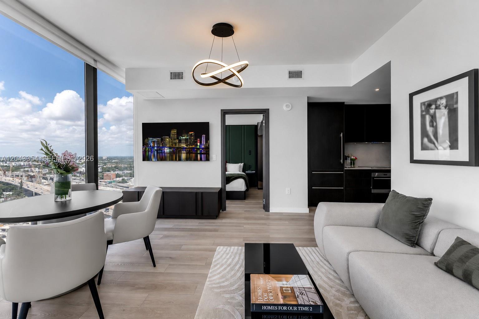 A modern living room features a sofa, dining area, and view of a city skyline — 20 NE 11th Street # 3410, Miami FL 33132, MIAMI, FL