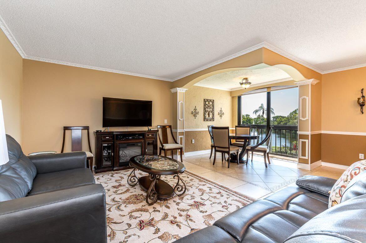 A living room with a leather sofa, television, and a dining area overlooking a lake — 1915 Lavers Circle # E309, Delray Beach FL 33444, DELRAY BEACH, FL